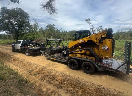 Skid steer and attachments loaded out on the trailer between jobs